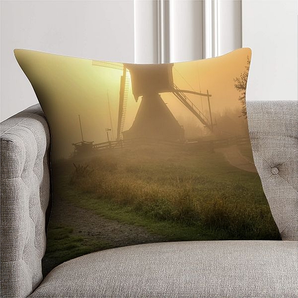 Wipmolen in Kinderdijk, de ochtendzon breekt door de mist en kleurt de lucht warm geel.